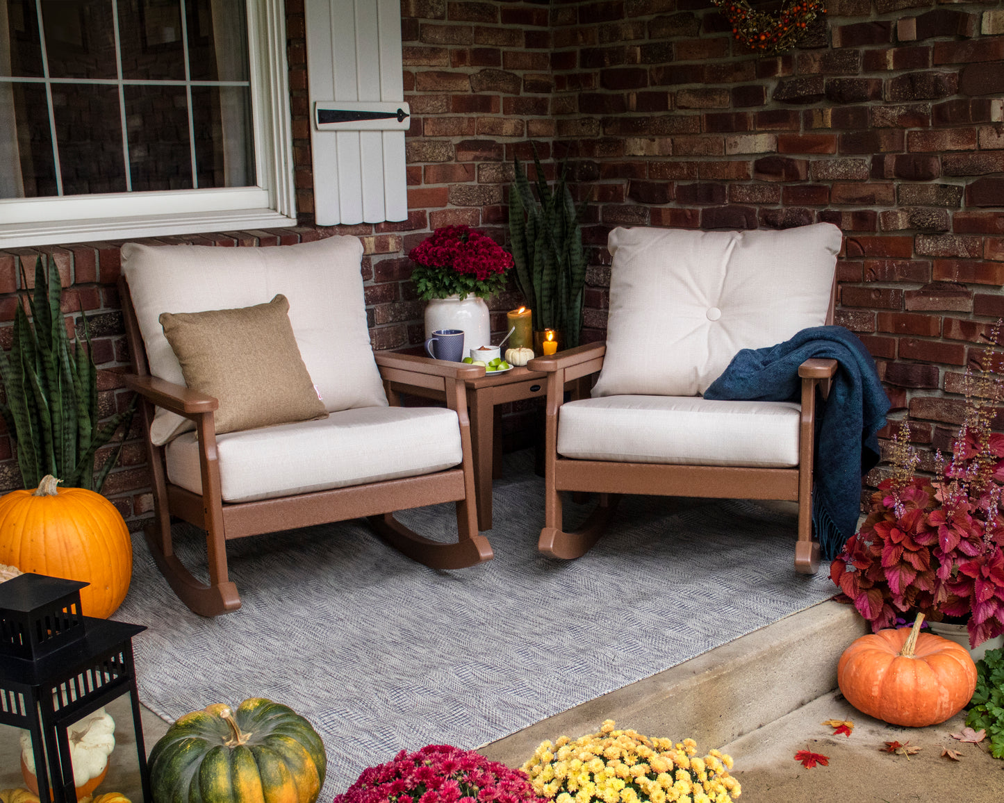 Two rocking chairs with autumn decorations placed around them, on front porch